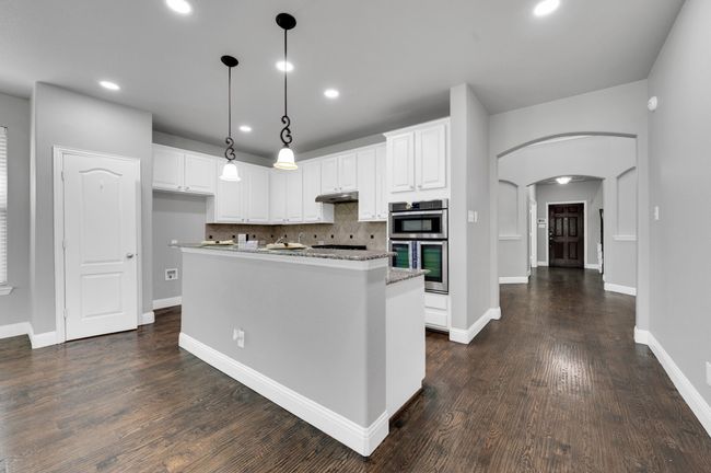 Kitchen featuring appliances with stainless steel finishes, arched walkways, white cabinetry, granite counters, breakfast bar and pantry. | Image 12