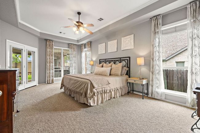 Carpeted bedroom featuring a tray ceiling, ornamental molding, and ceiling fan | Image 18