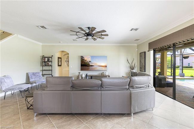 Living area featuring a ceiling fan, arched walkways, visible vents, and ornamental molding | Image 7