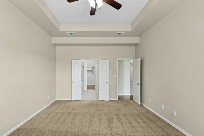 Unfurnished bedroom featuring carpet, baseboards, a tray ceiling, and ceiling fan | Image 15