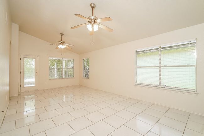 Empty room with vaulted ceiling, a ceiling fan, and light tile patterned floors | Image 5