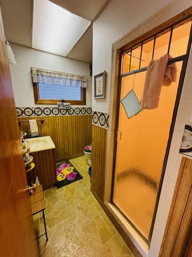 Bathroom featuring sink, toilet, an enclosed shower, and wood walls | Image 17
