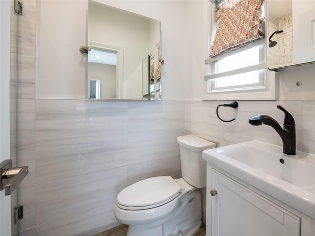 Half bath featuring tile walls, wainscoting, a sink, and toilet | Image 14