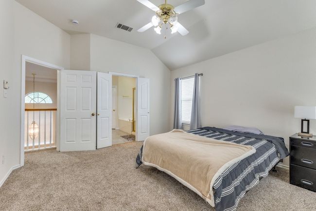 Bedroom with connected bathroom, lofted ceiling, visible vents, ceiling fan, and carpet | Image 16
