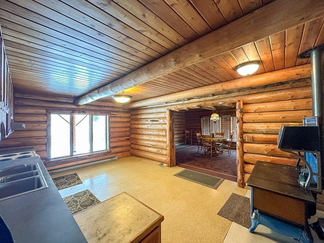Living room featuring beamed ceiling, rustic walls, and a wood stove | Image 22