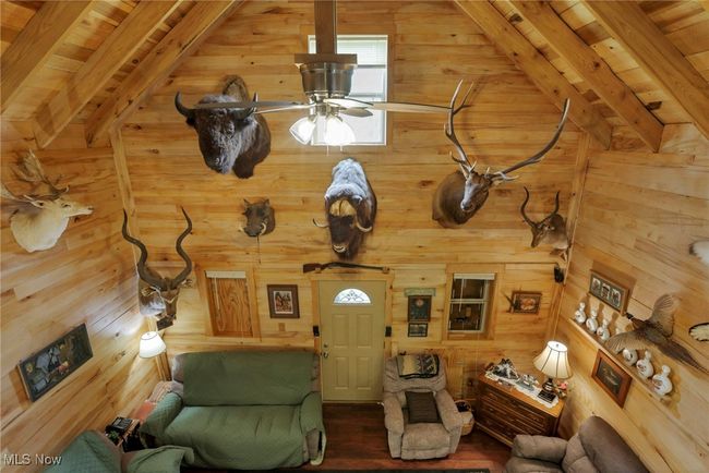 Living room with a ceiling fan, wood walls, wood finished floors, and wood ceiling | Image 20