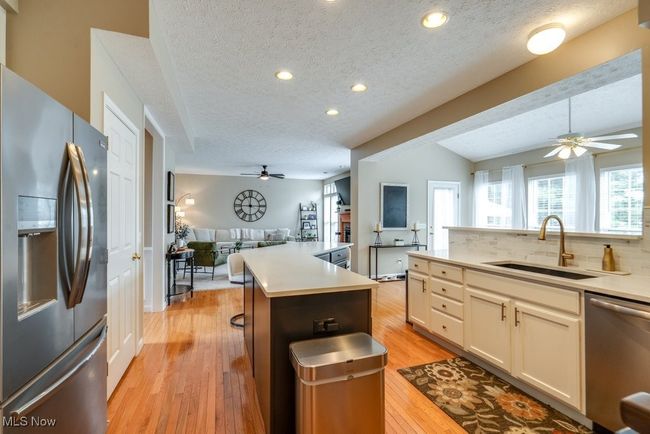 Kitchen with stainless steel appliances, a ceiling fan, open floor plan, a textured ceiling, and light wood finished floors | Image 6