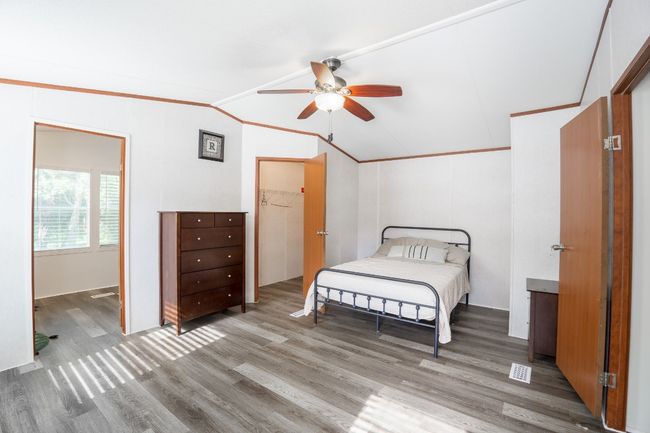 Bedroom featuring vaulted ceiling, wood finished floors, ornamental molding, and ceiling fan | Image 17