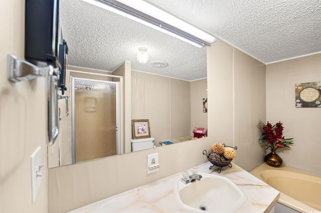 Full bathroom with a textured ceiling, vanity, a shower stall, and a garden tub | Image 7