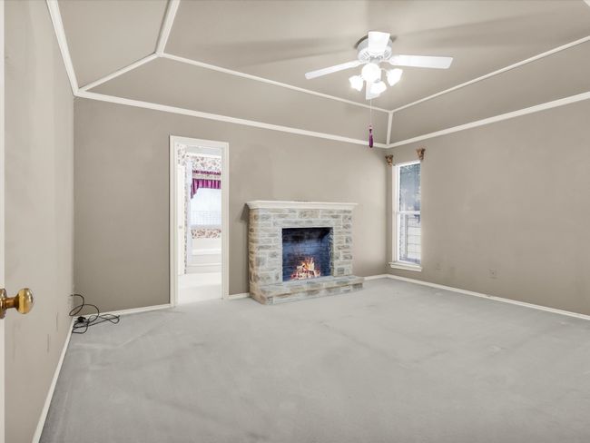 Primary bedroom with faux fireplace and access to en-suite bathroom. | Image 26