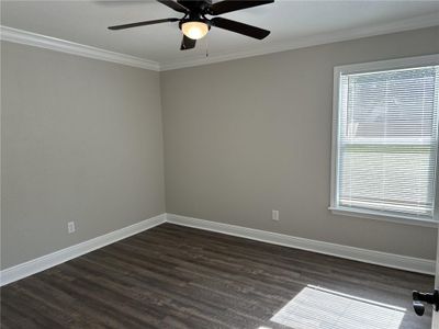 Apartment bedroom Unfurnished room with dark wood-type flooring, ceiling fan, a wealth of natural light, and crown molding | Image 3