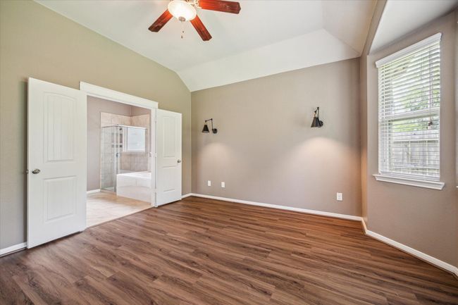 Elegant primary bedroom featuring exquisite wall molding, stylish sconces, and serene nature views. | Image 23