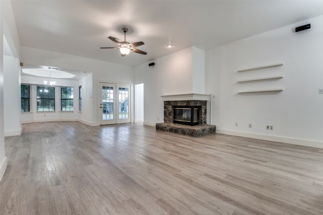 Unfurnished living room featuring light wood-style floors, a premium fireplace, ceiling fan, and a chandelier | Image 4