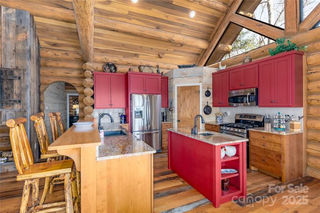 A spacious and functional kitchen island serves as the centerpiece creating a seamless flow to the adjoining living and dining areas for entertaining and family gatherings. Large windows and natural light enhance the airy, inviting ambiance of the modern kitchen | Image 13