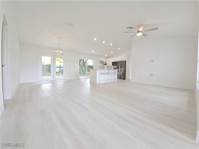Unfurnished living room with a chandelier, vaulted ceiling, a ceiling fan, recessed lighting, and light wood-style flooring | Image 11