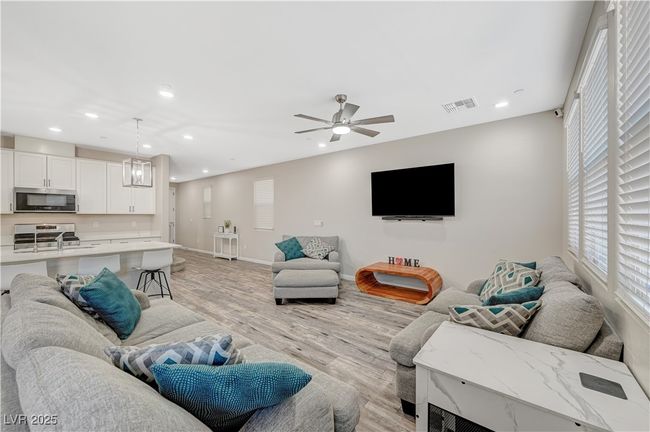 Living room with light wood-type flooring, recessed lighting, baseboards, and a ceiling fan | Image 13