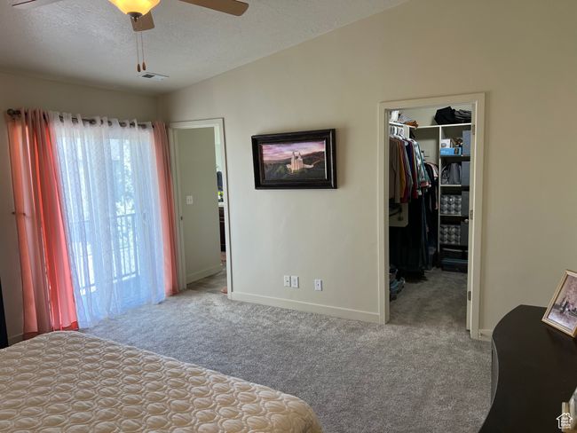 Bedroom featuring a textured ceiling, carpet flooring, a closet, baseboards, and a walk in closet | Image 30