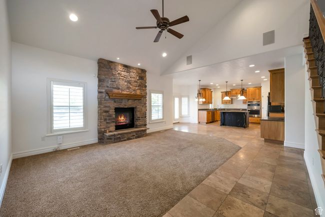 Unfurnished living room with baseboards, recessed lighting, a ceiling fan, high vaulted ceiling, and a stone fireplace | Image 6