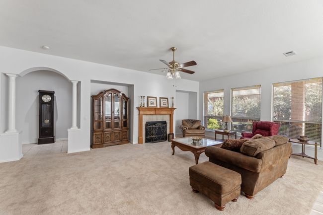 Living room featuring ornate columns, a tiled fireplace, light colored carpet, and ceiling fan | Image 13