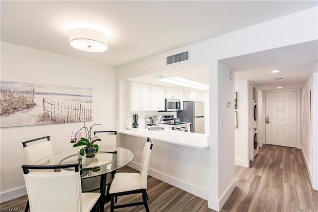 Dining space with baseboards, stacked washer and dryer, visible vents, and light wood-style flooring | Image 8