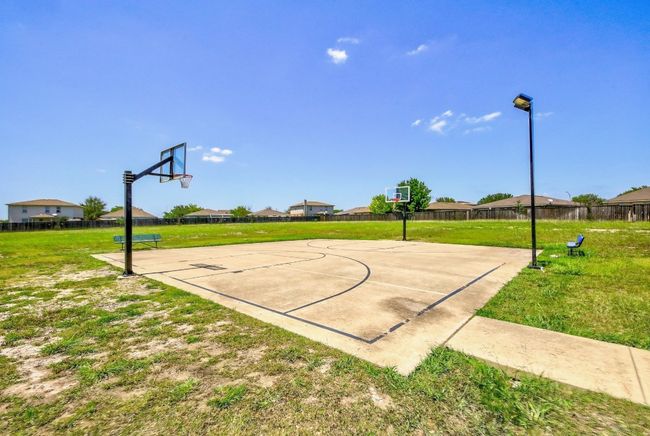 View of basketball court with a lawn, fence, and community basketball court | Image 40