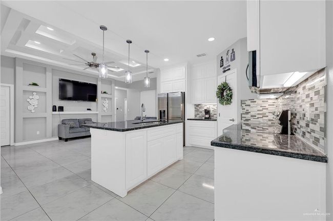 Kitchen with ceiling fan, stainless steel fridge, white cabinetry, dark stone countertops, and light marble finish floors | Image 5