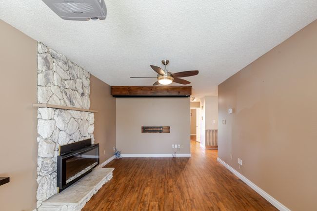 living room featuring a fireplace, wood finished floors, a textured ceiling, baseboards, and ceiling fan | Image 22