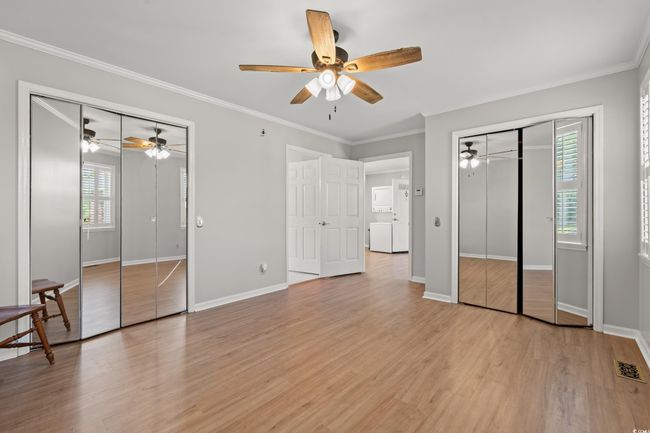 Unfurnished bedroom featuring multiple closets, ornamental molding, light wood-style floors, and a ceiling fan | Image 38