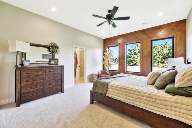 Bedroom with wood walls, vaulted ceiling, ceiling fan, and light colored carpet | Image 21