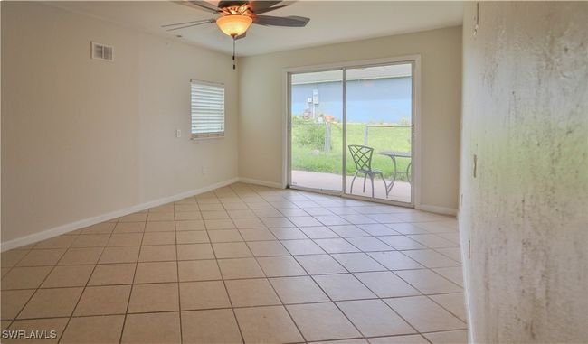 Empty room with ceiling fan, baseboards, and light tile patterned floors | Image 5