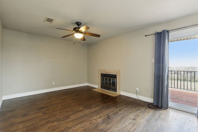 Unfurnished living room featuring a ceiling fan, baseboards, wood finished floors, visible vents, and a premium fireplace | Image 16