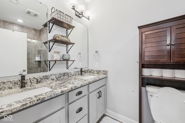 bathroom featuring baseboards, visible vents, tiled shower, and a sink | Image 15