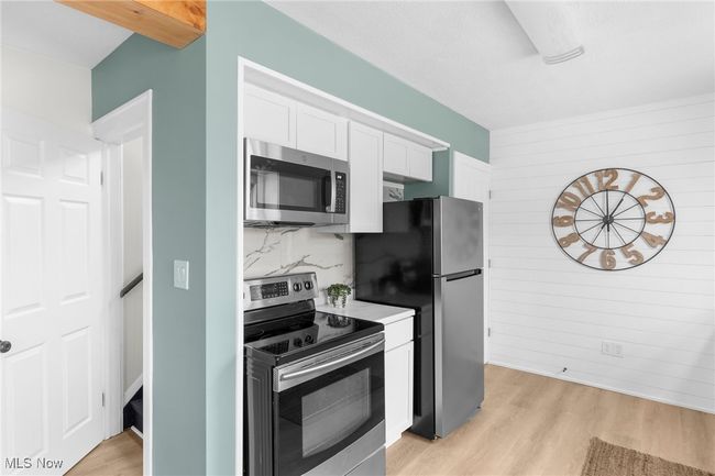 Kitchen featuring white cabinetry, tasteful backsplash, stainless steel appliances, and light wood-type flooring | Image 7