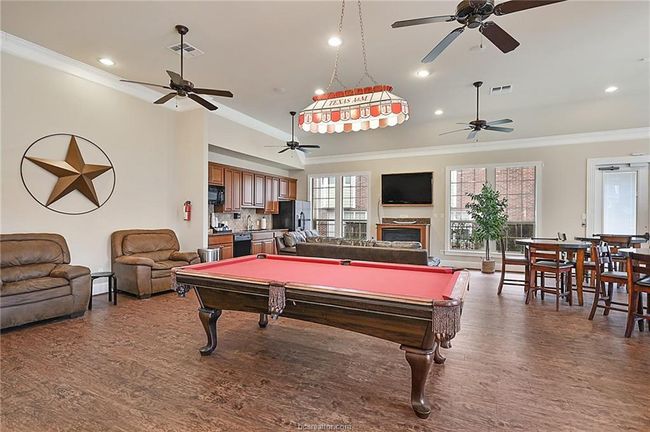Rec room with wood finished floors, visible vents, a ceiling fan, and ornamental molding | Image 29