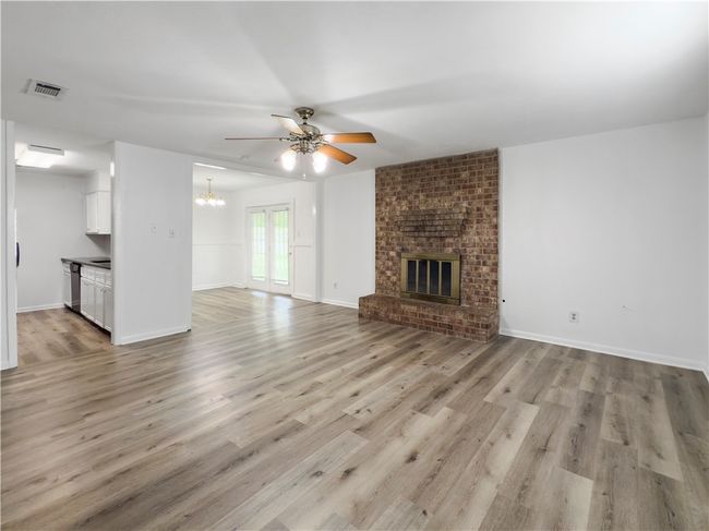 Unfurnished living room featuring a ceiling fan, a chandelier, light wood finished floors, and a fireplace | Image 5