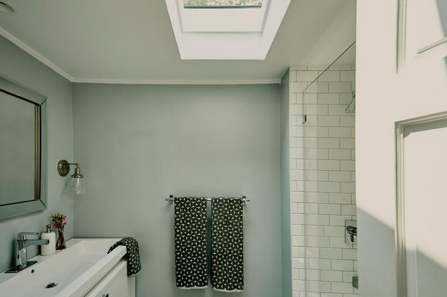 Bathroom featuring a skylight, ornamental molding, a tile shower, and vanity | Image 20