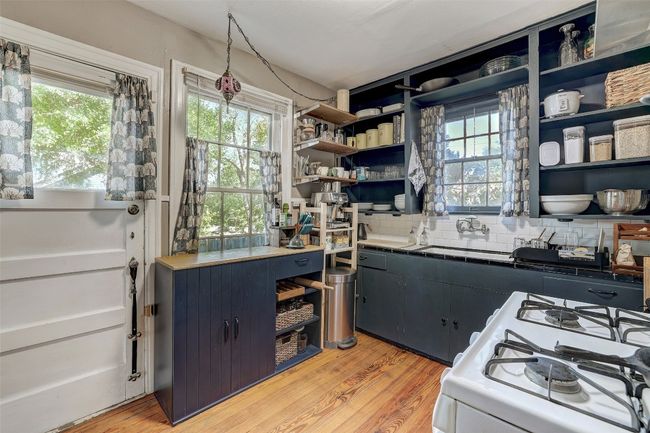 Kitchen featuring open shelves, a sink, decorative backsplash, light wood-style flooring, and white gas range oven | Image 12