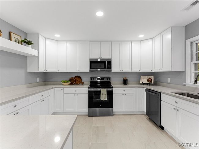 Kitchen with open shelves, white cabinetry, and stainless steel appliances | Image 18