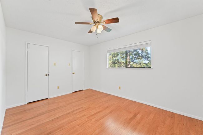 Bright and inviting, this bedroom features hardwood flooring, ample natural light, and a convenient ceiling fan. Ideal for comfort and relaxation. | Image 19