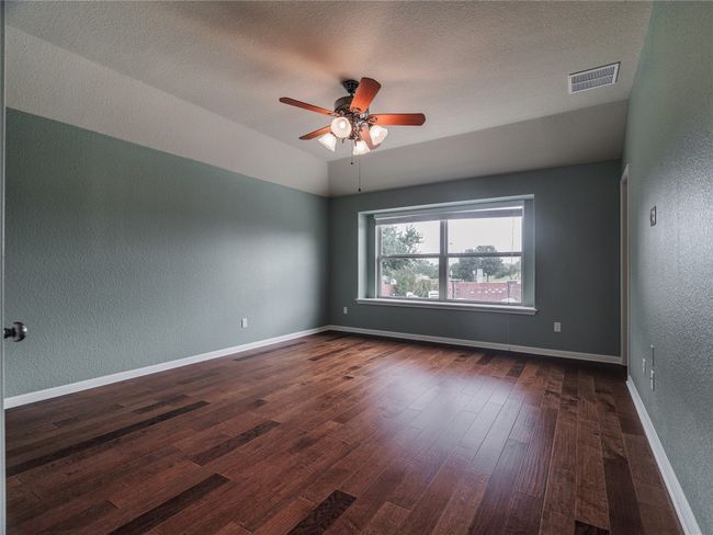 Unfurnished room with a textured wall, dark wood-style flooring, a ceiling fan, a textured ceiling, and lofted ceiling | Image 23