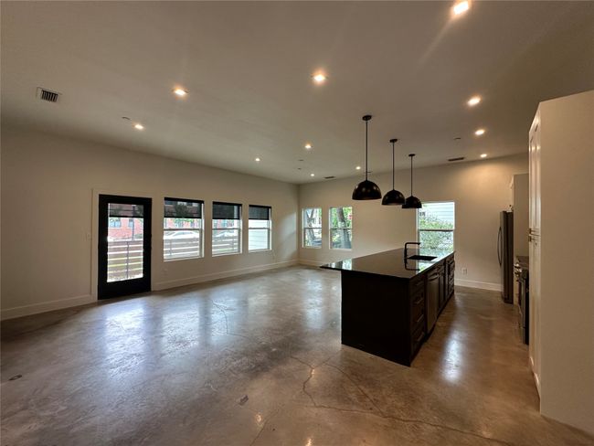 Kitchen with recessed lighting, finished concrete flooring, open floor plan, an island with sink, and white cabinetry | Image 19