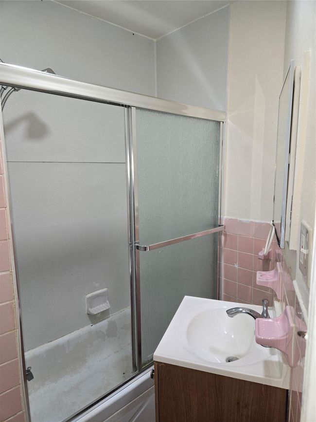 Full bath with an enclosed shower, vanity, tile walls, and a wainscoted wall | Image 12