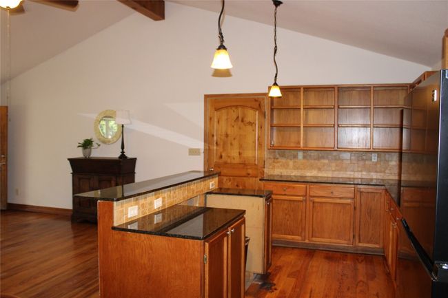Kitchen featuring freestanding refrigerator, dark wood-type flooring, backsplash, and open shelves | Image 6