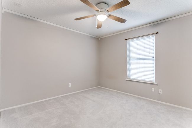 Spare room featuring light carpet, crown molding, a ceiling fan, and a textured ceiling | Image 20