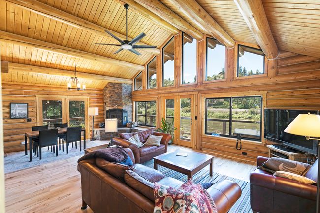 Living area with log walls, plenty of natural light, a stone fireplace, wooden ceiling with exposed beams, and high vaulted ceiling | Image 18