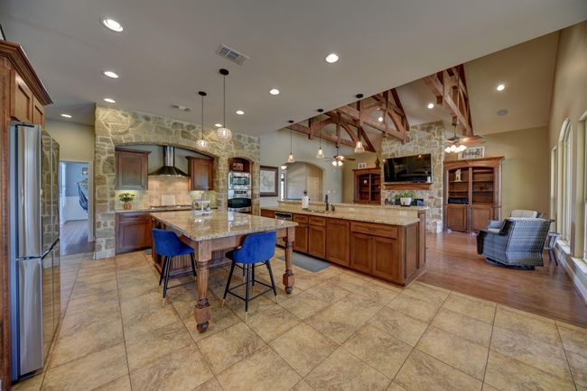 Spacious kitchen with a stone accent wall and expansive island—perfect for entertaining and culinary creativity. | Image 10