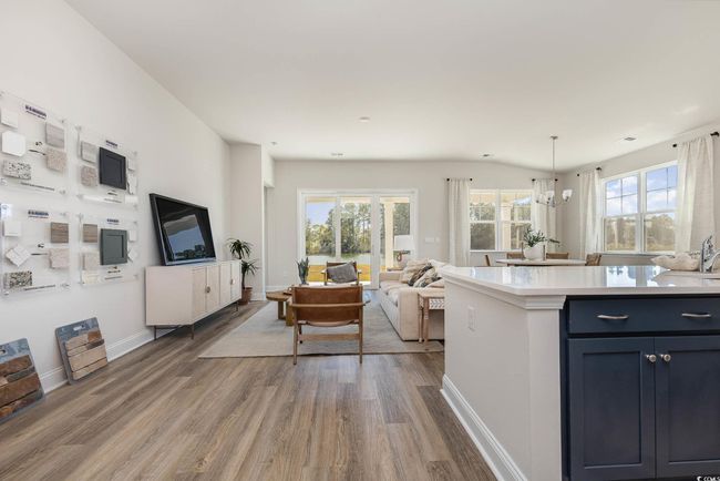 Kitchen featuring wood finished floors, light countertops, baseboards, a chandelier, and open floor plan | Image 6