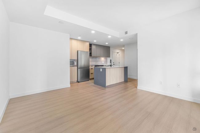 Kitchen with open shelves, a kitchen island with sink, light wood-style floors, appliances with stainless steel finishes, and modern cabinets | Image 8