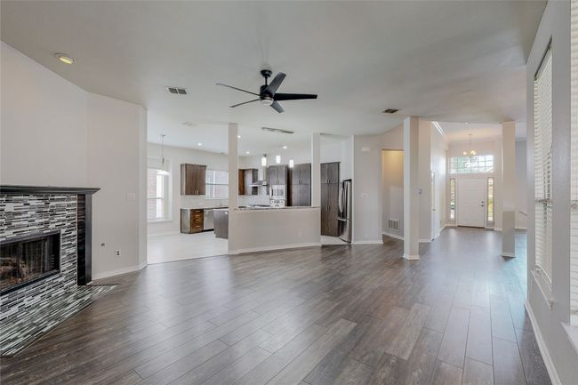 Unfurnished living room with healthy amount of natural light, dark wood finished floors, a fireplace, and recessed lighting | Image 11