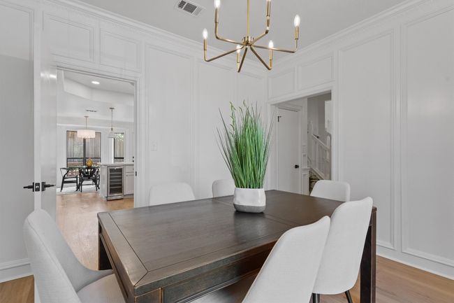Dining room with a chandelier, beverage cooler, stairs, light wood-type flooring, and a decorative wall | Image 13